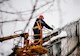 A worker on a crane knocking down huge icicles